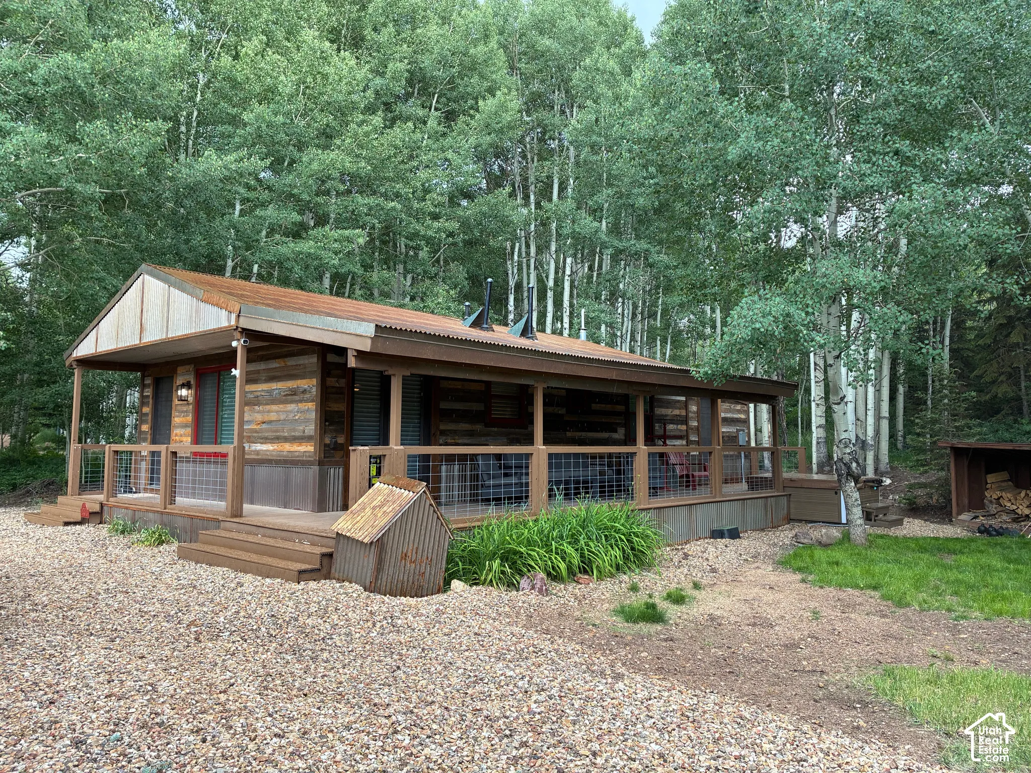 Exterior featuring horizontal wood siding, corrugated metal roofing, and an expansive wraparound deck with wire mesh railing
