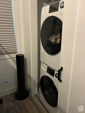 Built-in stacked front-load laundry unit with digital controls, recessed installation, and wood-finish flooring
