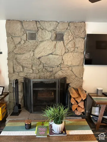 Floor-to-ceiling natural stone fireplace surround with integrated metal fire screen and stone hearth