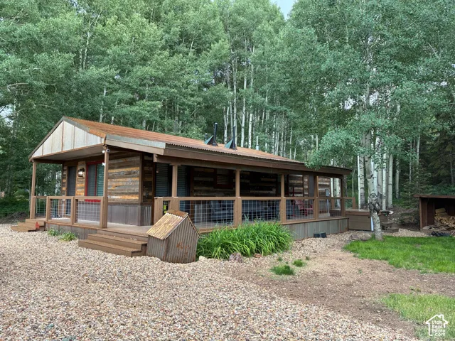 Exterior featuring horizontal wood siding, corrugated metal roofing, and an expansive wraparound deck with wire mesh railing