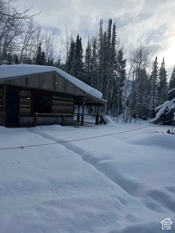 Cabin exterior featuring horizontal wood siding, metal roofing, and a covered porch with metal railing