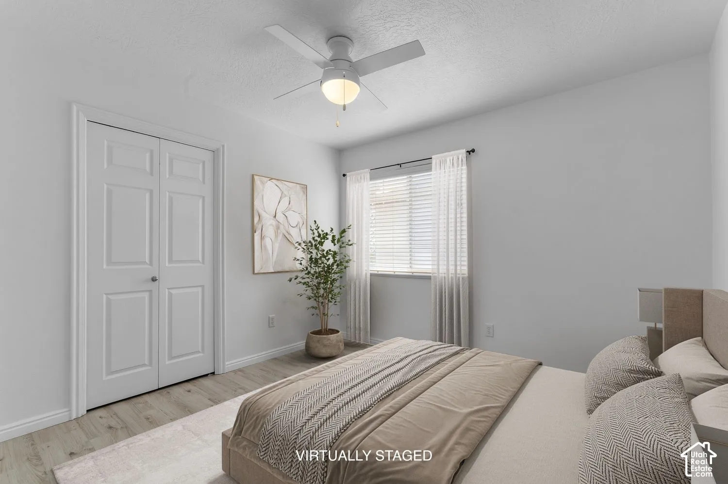 Bedroom featuring wood-finish flooring, a ceiling fan with integrated lighting, and a double-door closet