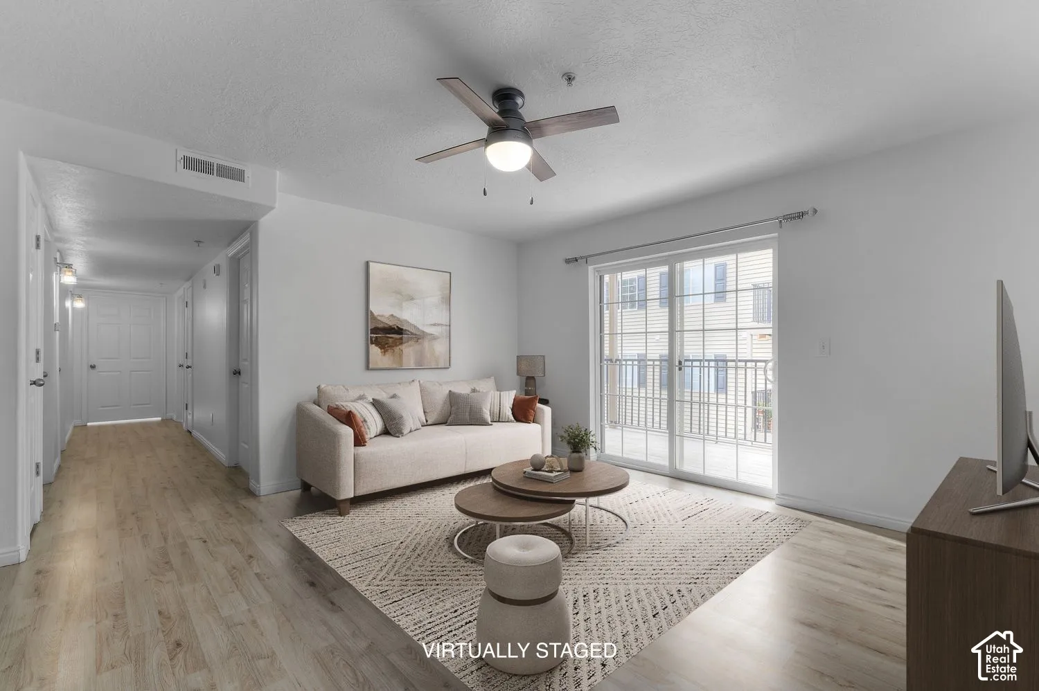 Wood-finish flooring, sliding glass door with exterior balcony access, and a ceiling fan with integrated lighting