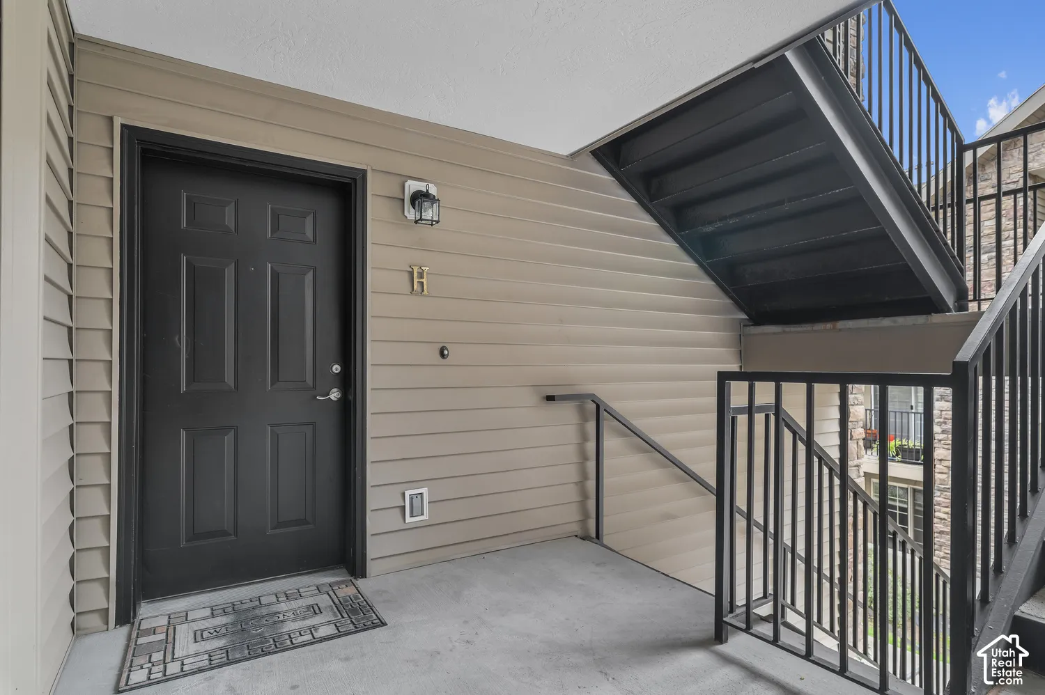 Entry featuring a paneled door, horizontal siding, and black metal staircase railing