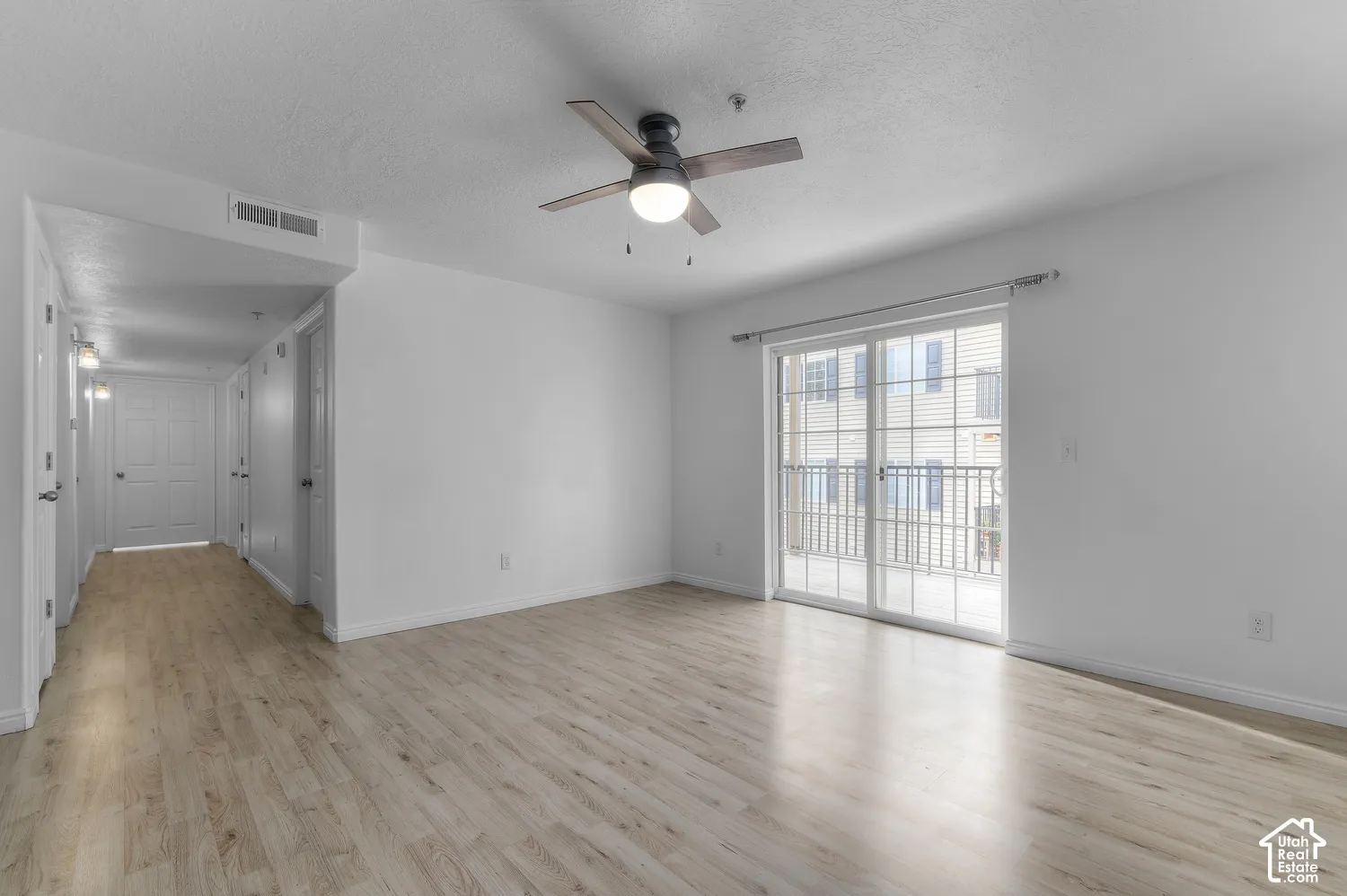 Interior space featuring wood-finish flooring, sliding glass doors, and a ceiling-mounted light fixture with a fan