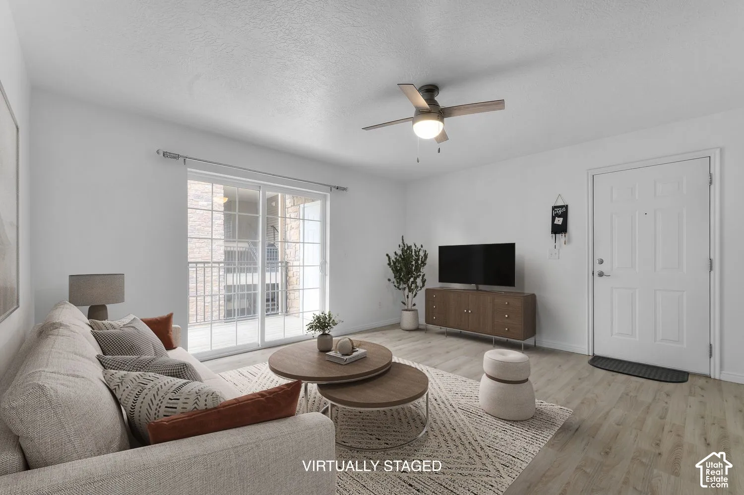 Living area featuring wood-finish flooring, a ceiling fan with integrated lighting, and a sliding glass door providing external access