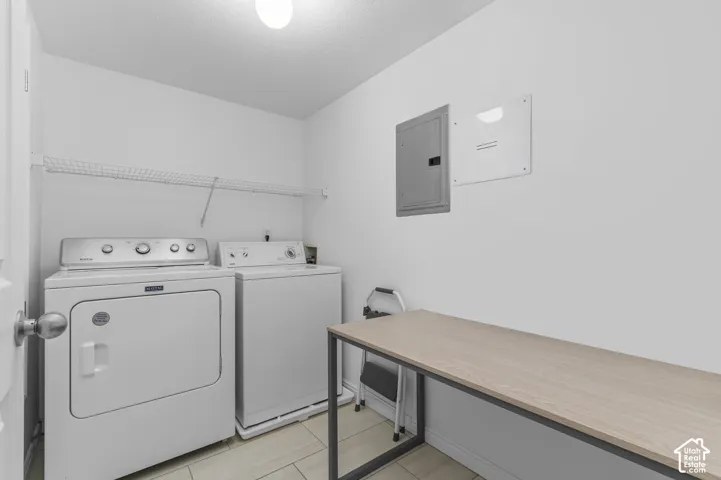 Dedicated utility space featuring tile flooring, wall-mounted wire shelving, and a built-in electrical service panel