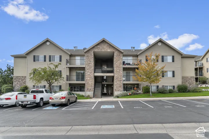 Multi-level exterior featuring horizontal siding, decorative stone veneer accents, recessed balconies with metal railings, and a central stairwell