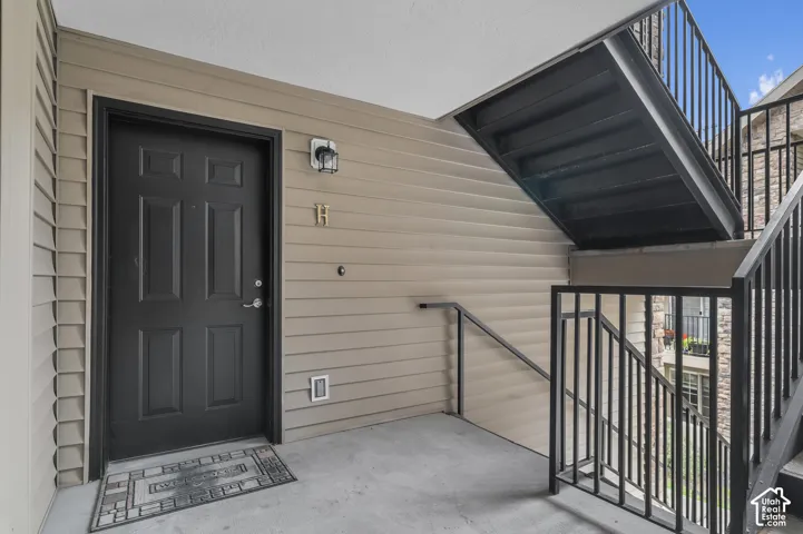 Entry featuring a paneled door, horizontal siding, and black metal staircase railing