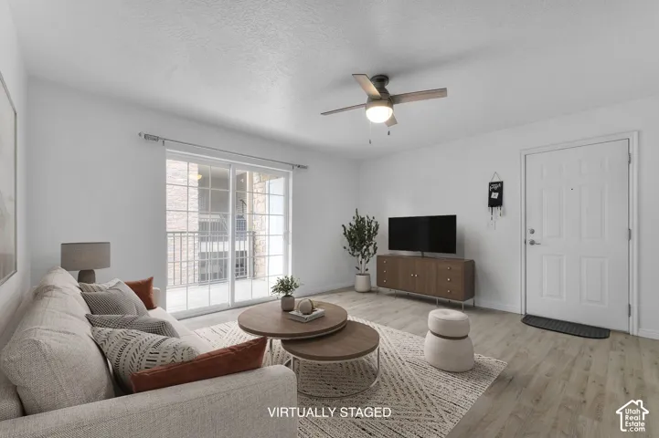 Living area featuring wood-finish flooring, a ceiling fan with integrated lighting, and a sliding glass door providing external access