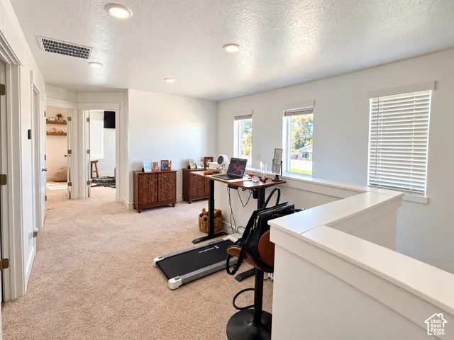 Open-concept space featuring neutral carpeting, recessed ceiling lighting, and multiple windows with horizontal blinds