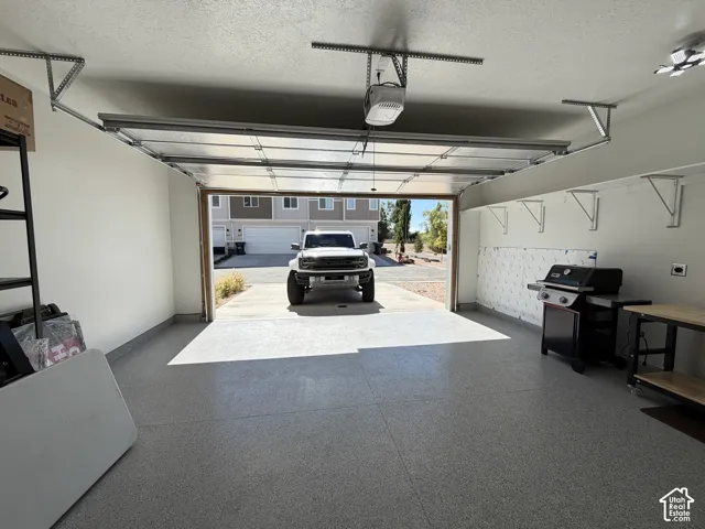 Two-car garage featuring epoxy-coated flooring, overhead lighting, and wall-mounted shelving brackets