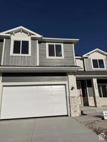 Exterior featuring horizontal and vertical siding, stone masonry accents, multiple gables, and a double-bay garage