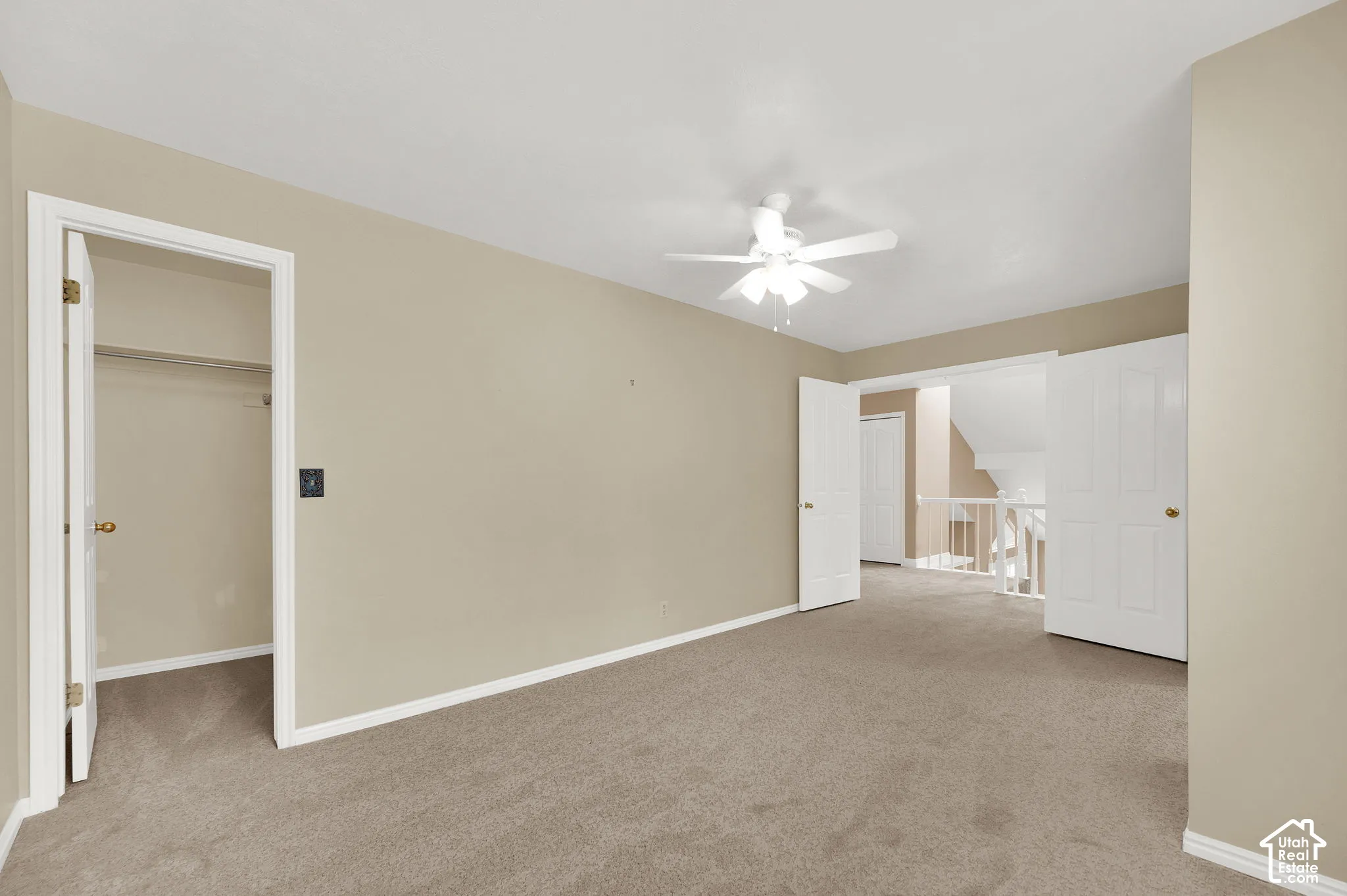 Room featuring neutral carpeting, a ceiling fan with integrated lighting, a walk-in closet, and white interior doors