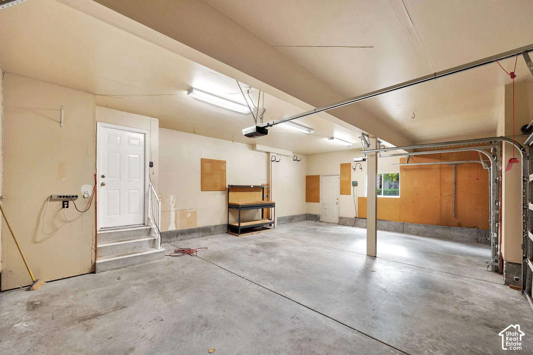 Multi-car garage featuring a concrete floor, built-in workbench, fluorescent lighting, and two separate exterior access doors