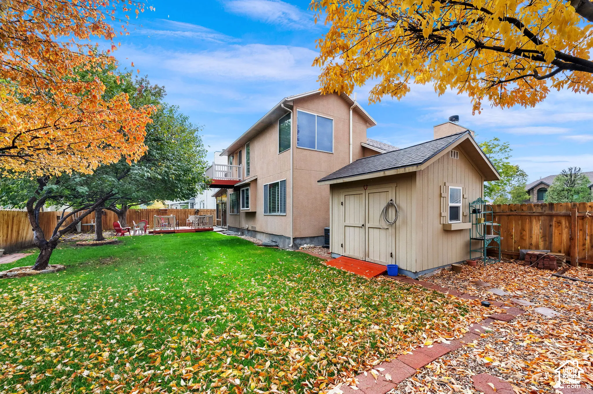 Spacious backyard featuring a manicured lawn, detached storage shed, wood fence enclosure, and mature trees