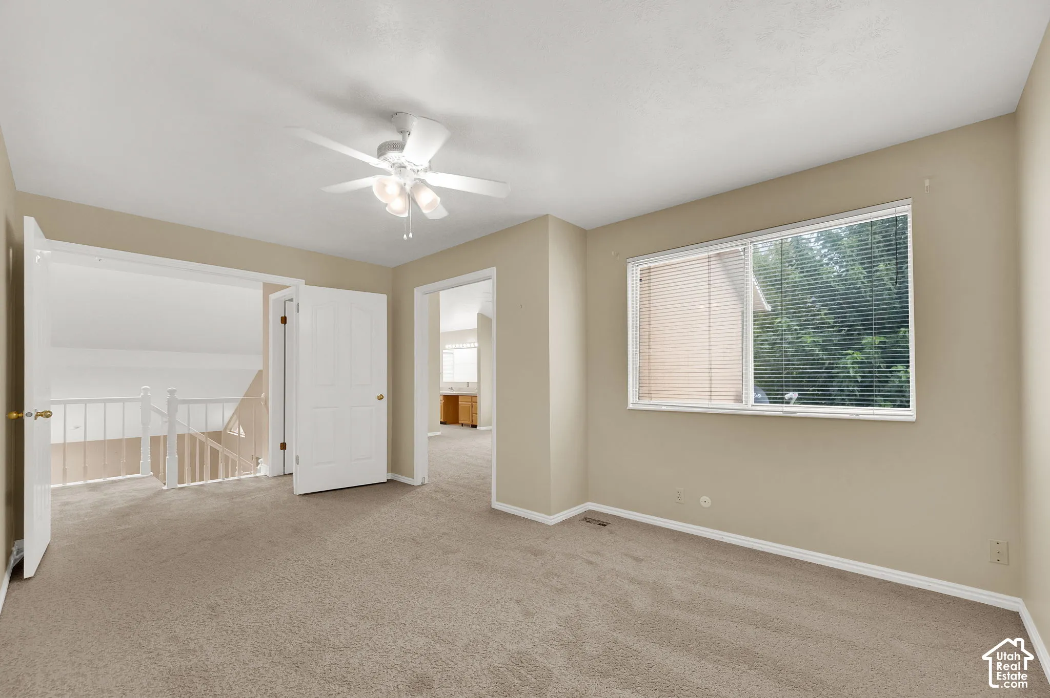 Carpeted interior room featuring a multi-light ceiling fan and a large horizontal sliding window with interior blinds