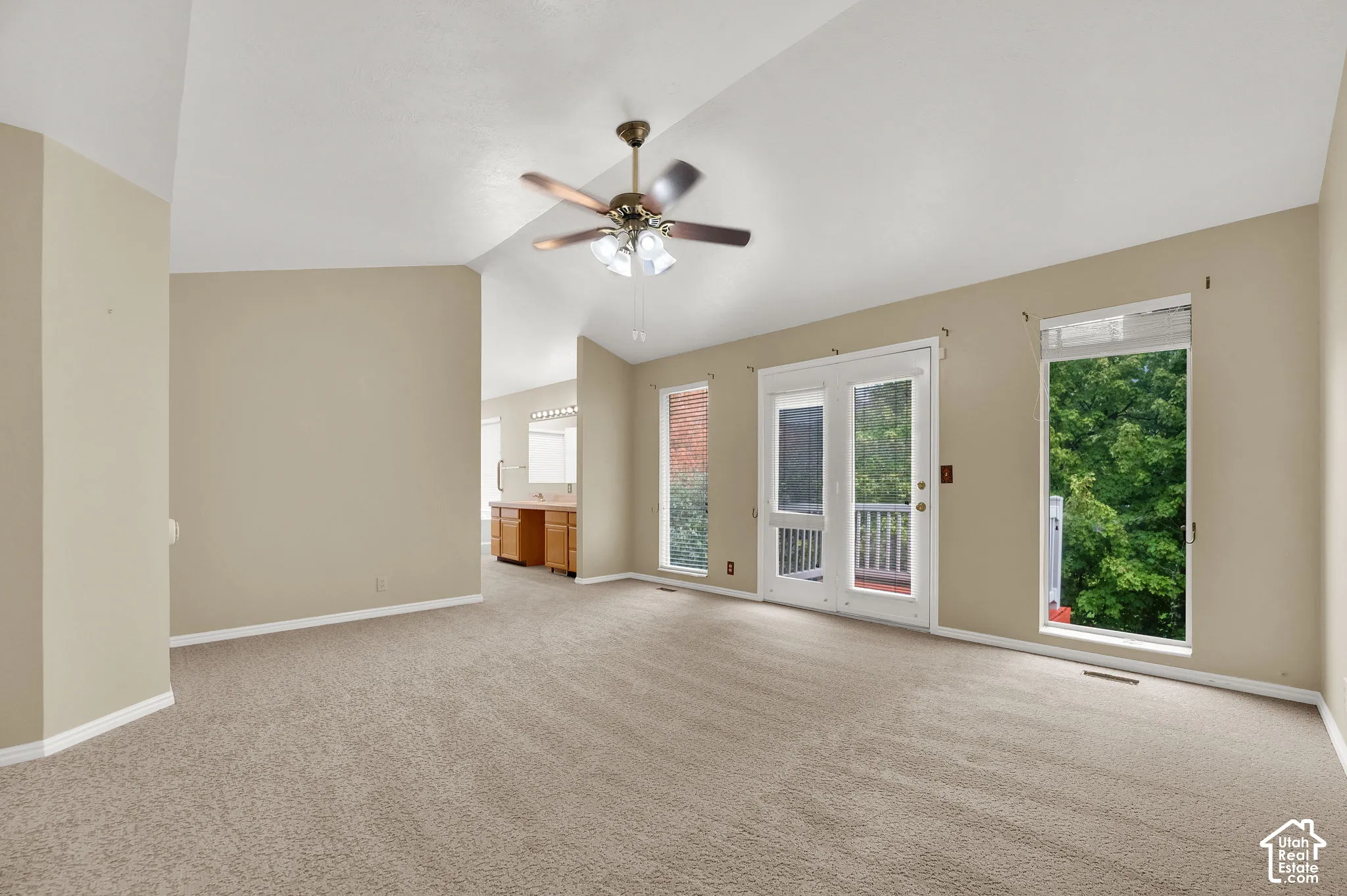 Vaulted ceilings featuring a central overhead fan, dual vertical windows, and glass-paneled exterior door