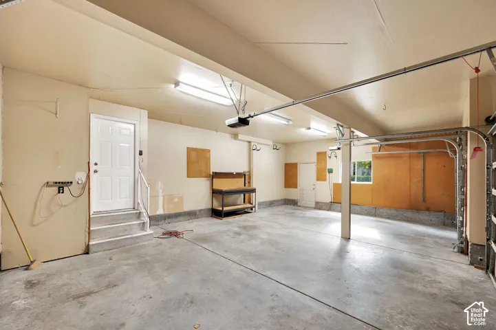 Multi-car garage featuring a concrete floor, built-in workbench, fluorescent lighting, and two separate exterior access doors