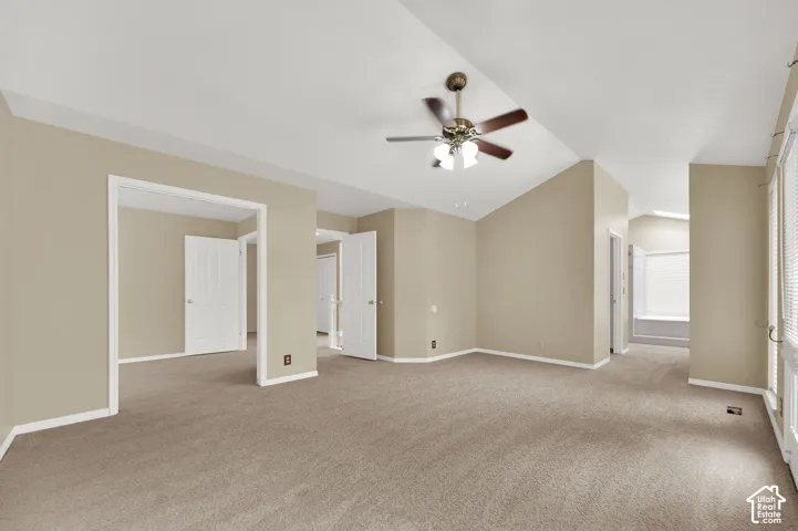 Vaulted ceilings, neutral carpeted flooring, integrated ceiling fan with light fixture, and classic white interior doors