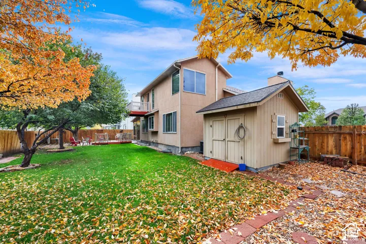 Spacious backyard featuring a manicured lawn, detached storage shed, wood fence enclosure, and mature trees