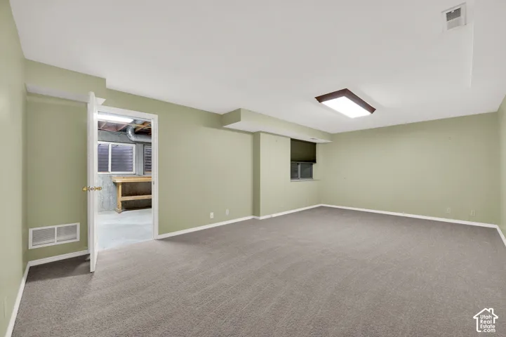 Open-concept room featuring neutral-toned carpeting, rectangular flush-mount lighting, and dual inset windows
