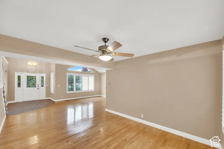 Wood-finish flooring, central ceiling fan with integrated lighting, multi-pane window with arched transom, and tile-floored entryway