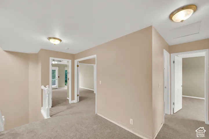 Neutral-toned interior featuring wall-to-wall carpeting, flush-mount ceiling light fixtures, white interior doors, and a white balustrade