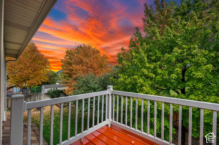 Elevated deck featuring painted wood-finish decking and white picket-style railings, overlooking a grassy yard with mature trees