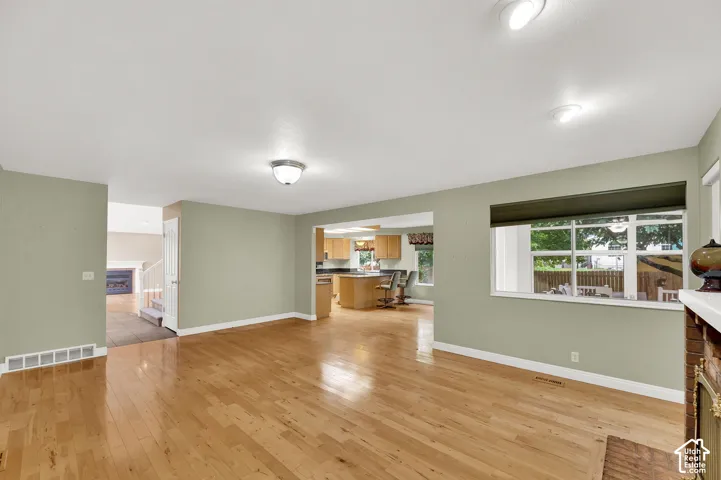 Open-concept interior featuring wood-finish flooring, a brick fireplace surround, neutral wall tones, and recessed ceiling lighting