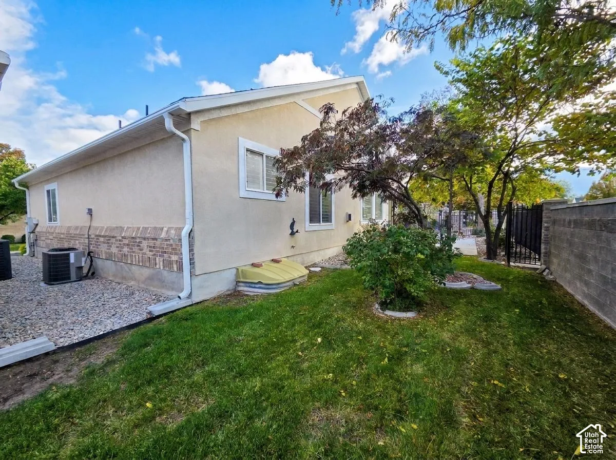 Stucco exterior featuring partial brick masonry accents, a manicured lawn, and a perimeter concrete block wall
