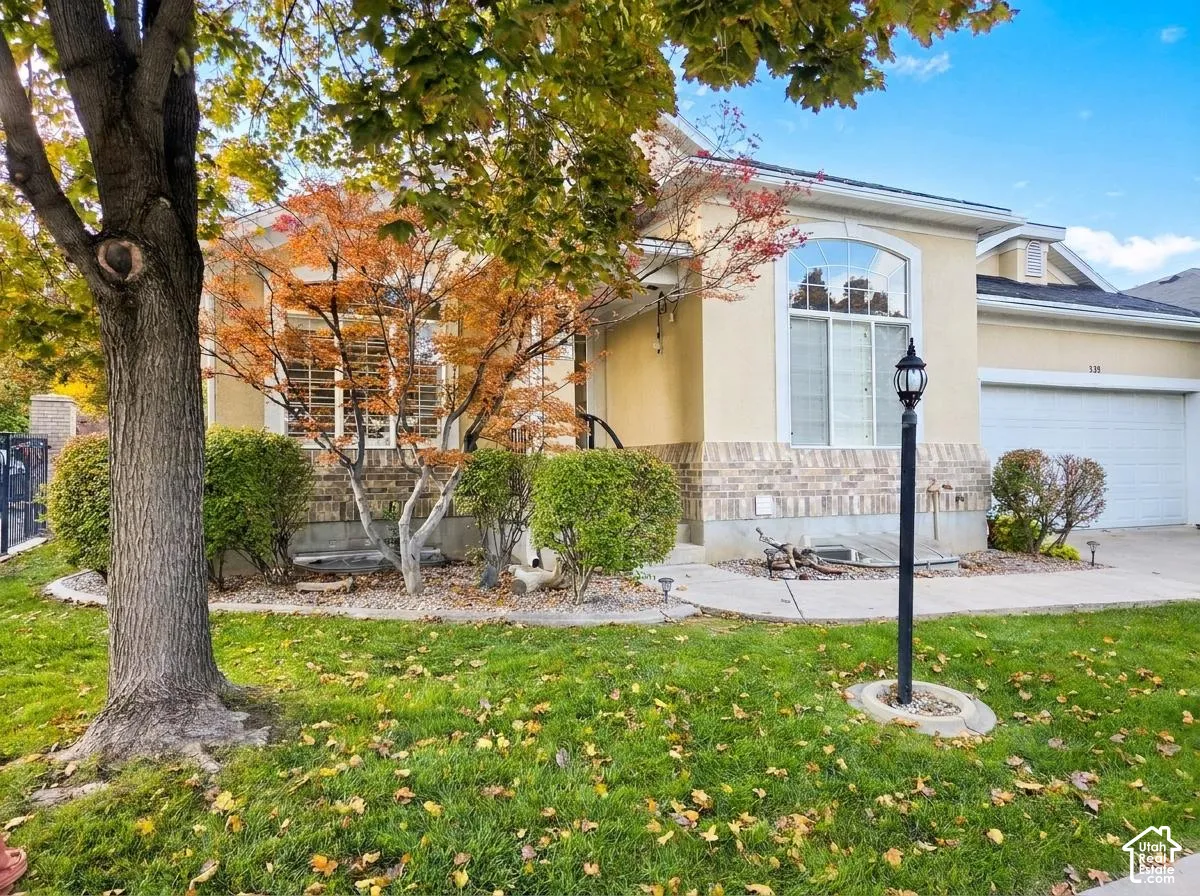 Stucco and brick facade featuring an arched window, decorative landscaping, and an attached two-car garage