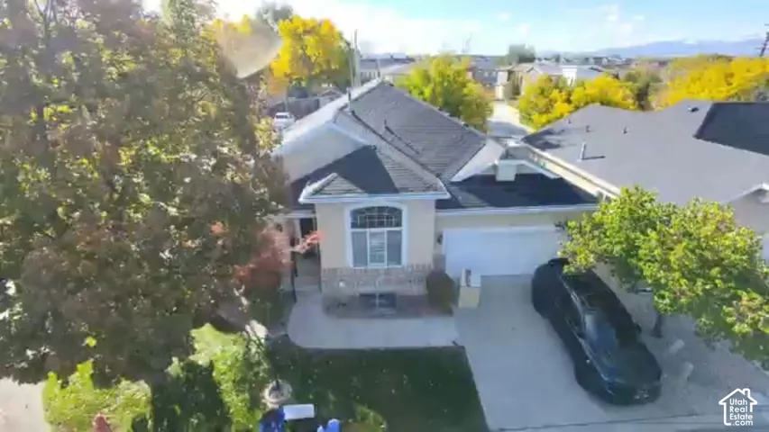 Single-story residence featuring a multi-gable roofline, stone and stucco facade, arched window detailing, and an attached two-car garage