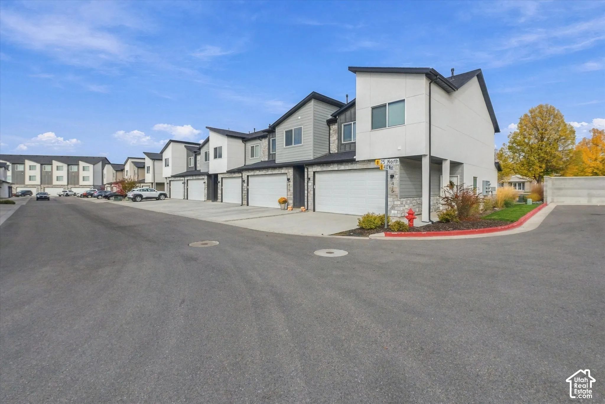 Multi-unit townhouse exterior featuring mixed-material siding, stone veneer accents, multi-pitched rooflines, and attached garages