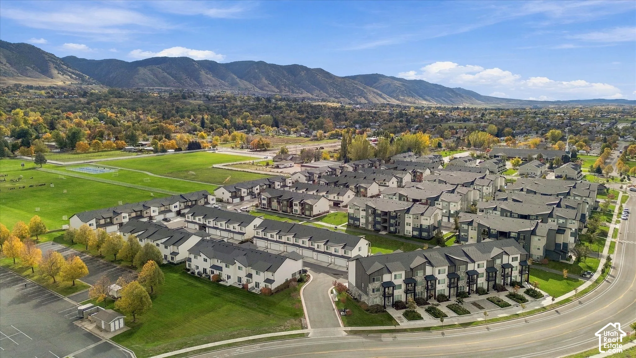 Multi-family residential complex featuring shingled roofs, private garage access, asphalt-paved driveways, and expansive mountain backdrops