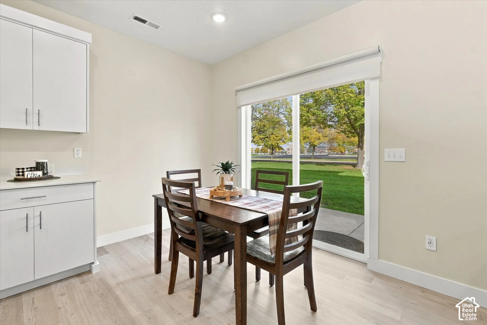 White shaker-style cabinetry, recessed ceiling lighting, sliding glass door, and wood-finish flooring