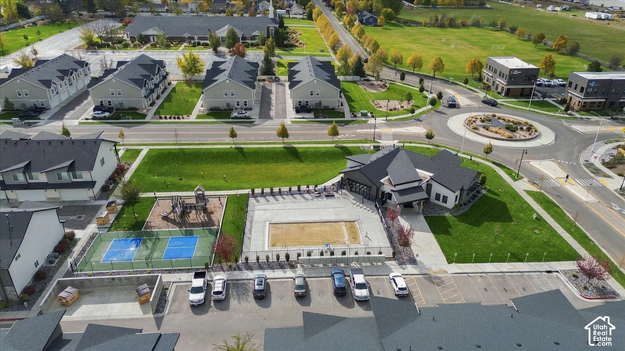 Community recreation area featuring an outdoor swimming pool, fenced sport court, playground equipment, and multi-purpose clubhouse facility