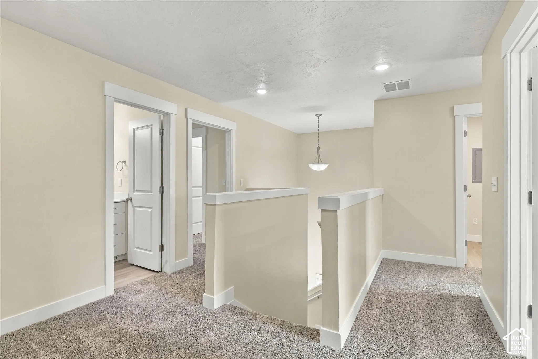 Neutral carpeting, recessed lighting, white door casings, and a multi-light pendant fixture