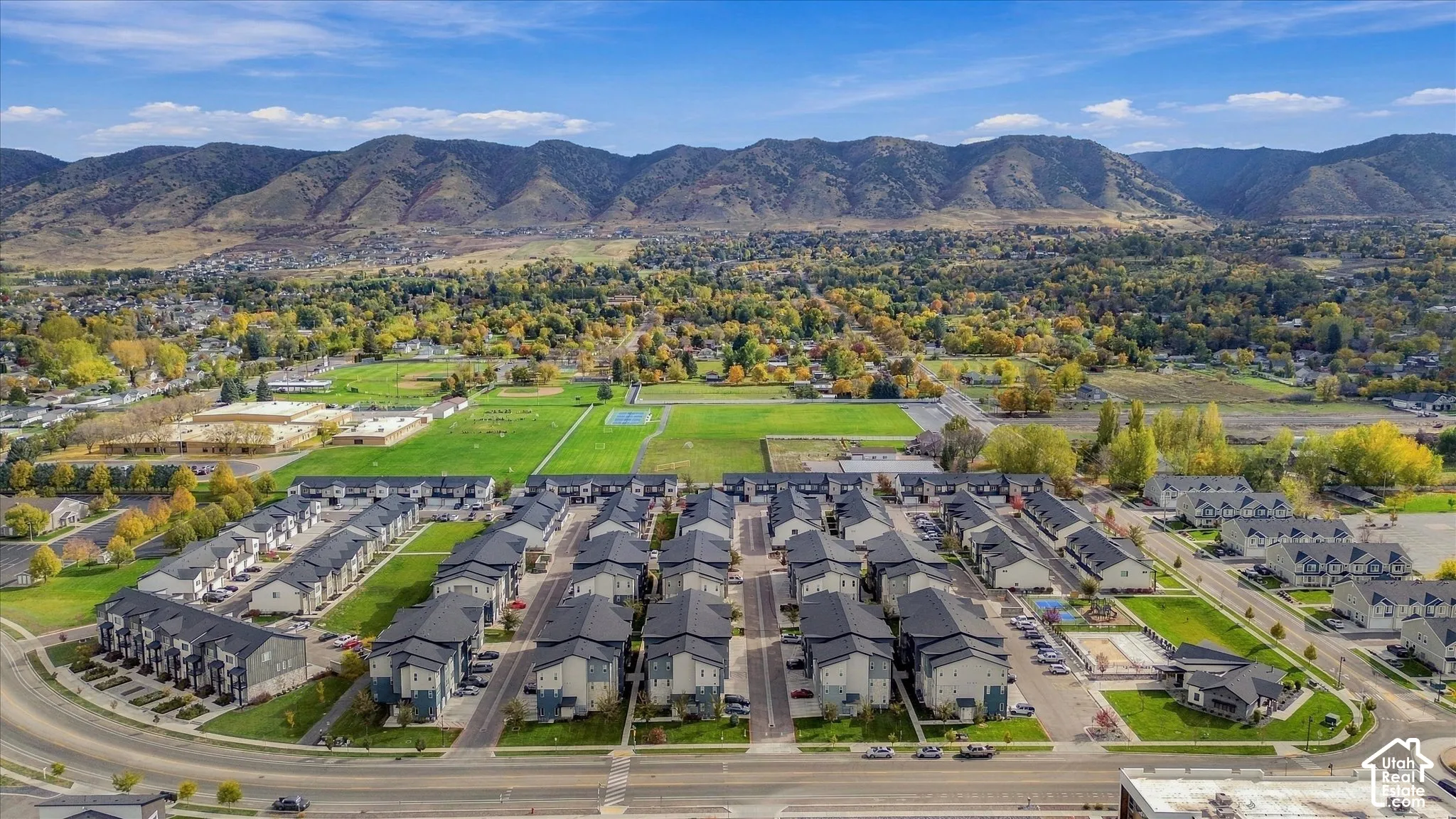 Aerial perspective of a multi-unit residential complex featuring multi-story siding exteriors, pitched roofs, private paved roadways, and a prominent mountain backdrop