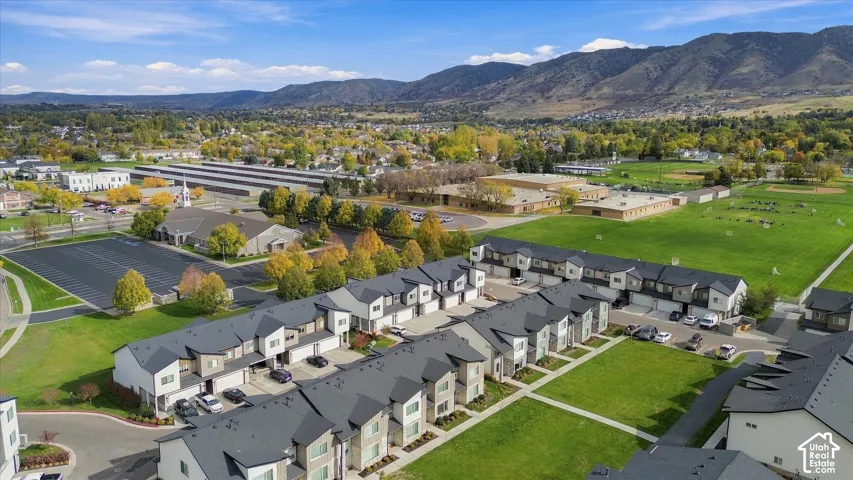 Aerial view of multi-unit residential complex featuring asphalt shingle roofing, attached garages, stone and siding exterior finishes, and shared green space