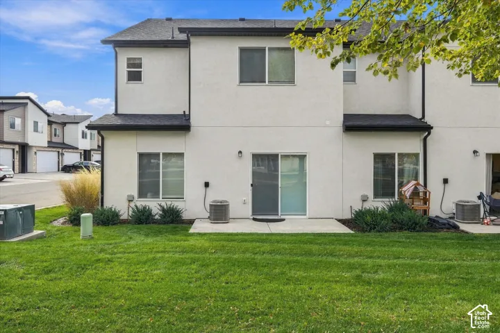Stucco exterior featuring a concrete patio, sliding glass door, and green space