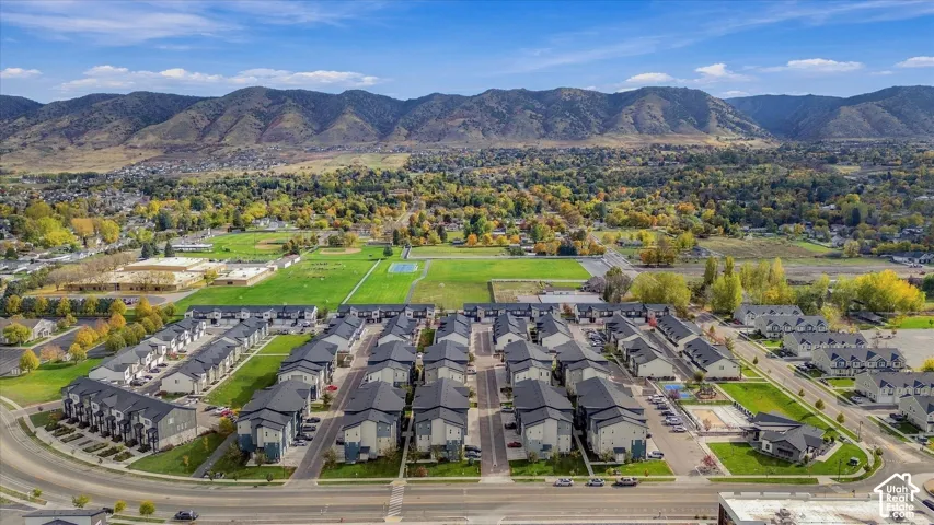 Aerial perspective of a multi-unit residential complex featuring multi-story siding exteriors, pitched roofs, private paved roadways, and a prominent mountain backdrop