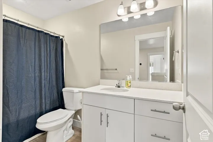 Bathroom featuring a white vanity with integrated basin, solid surface countertop, large wall-mounted mirror, polished chrome light fixture, and combination tub with shower