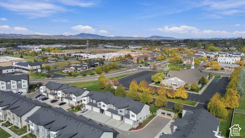Aerial perspective of a multi-unit residential complex featuring asphalt shingle roofs, private garages, concrete driveways, and expansive mountain scenery