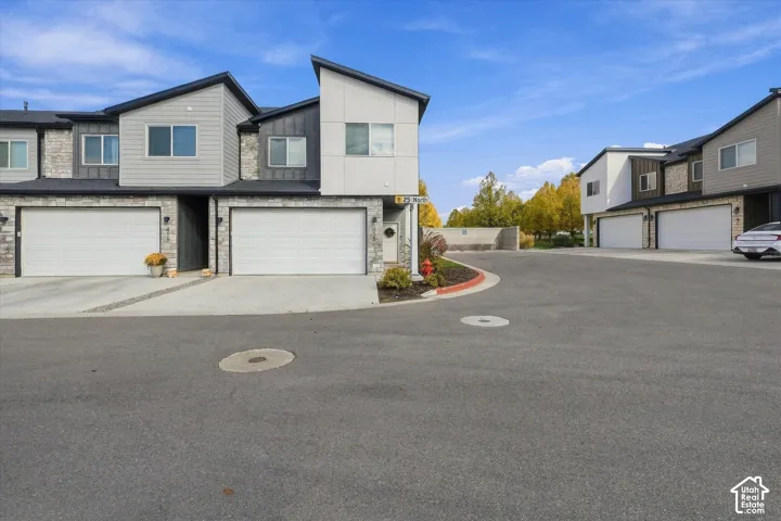 Modern multi-story end-unit featuring a mix of stone veneer and horizontal siding, shed-style rooflines, and attached 2 car garage