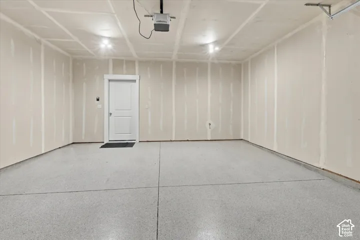 Multi-car garage featuring epoxy-coated flooring, an automated overhead door opener, and a single-panel interior access door