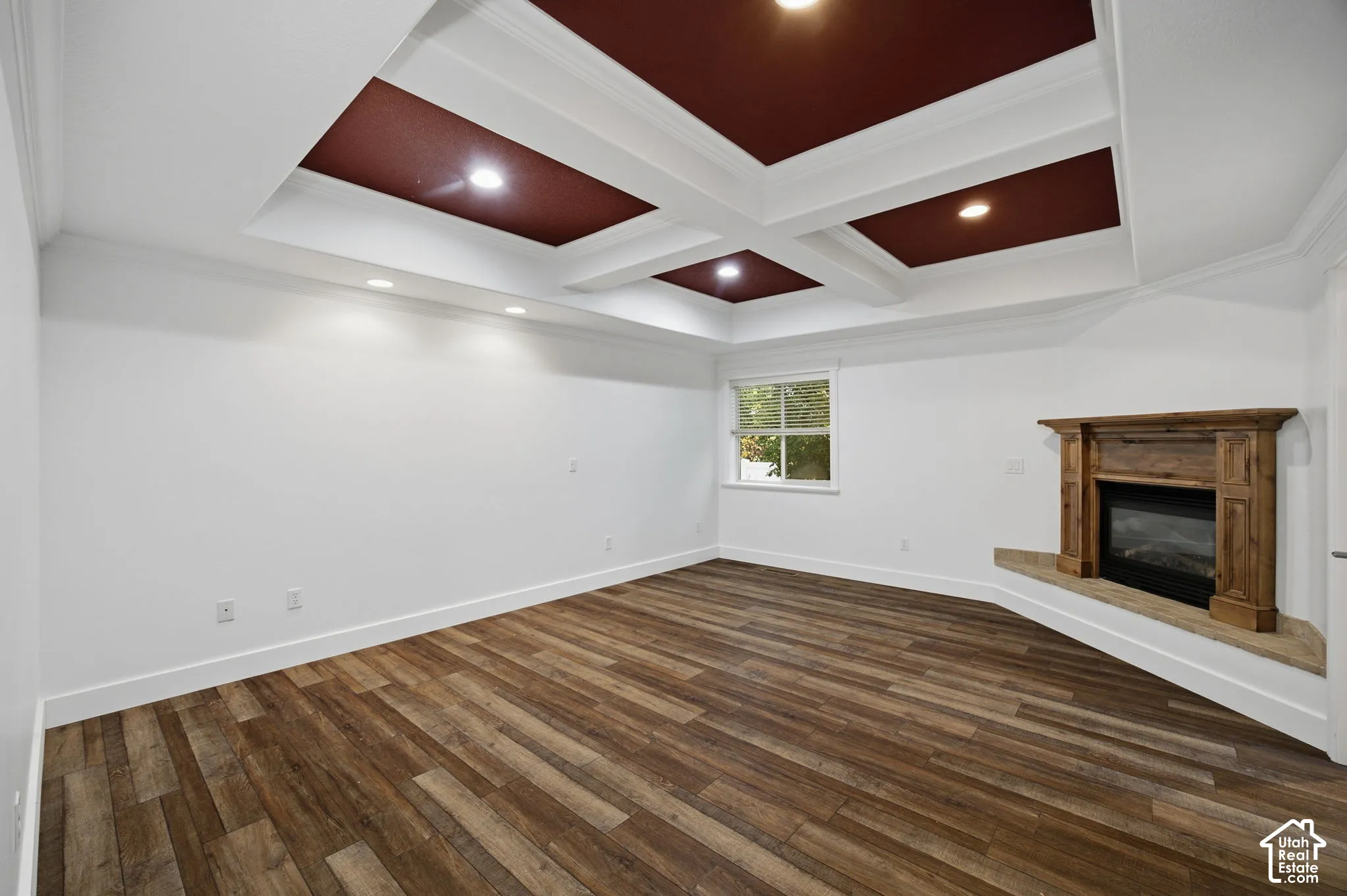 Coffered ceiling with recessed lighting, wood-finish flooring, and a fireplace with a wood mantel and stone-finish hearth