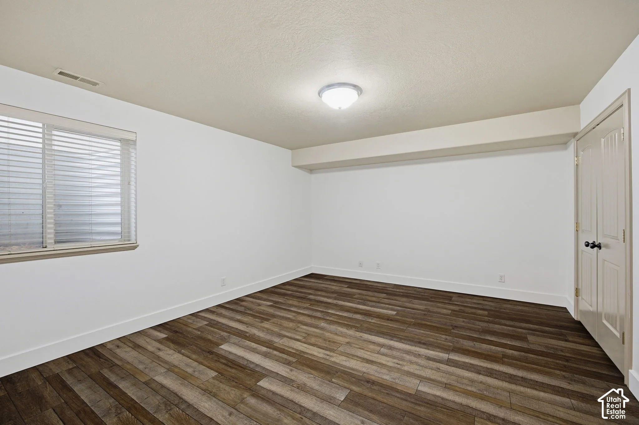 Room featuring neutral wall paint, wood-finish flooring, a recessed window, and double-panel doors