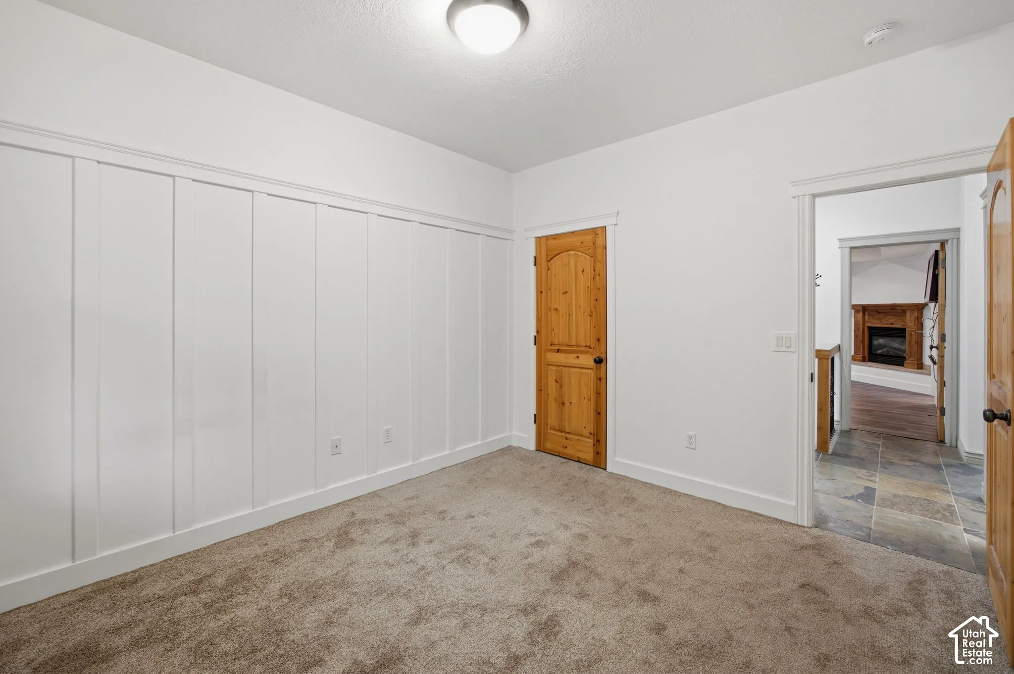 Room featuring wall-to-wall carpeting, white board-and-batten wall detailing, and a solid wood arched door