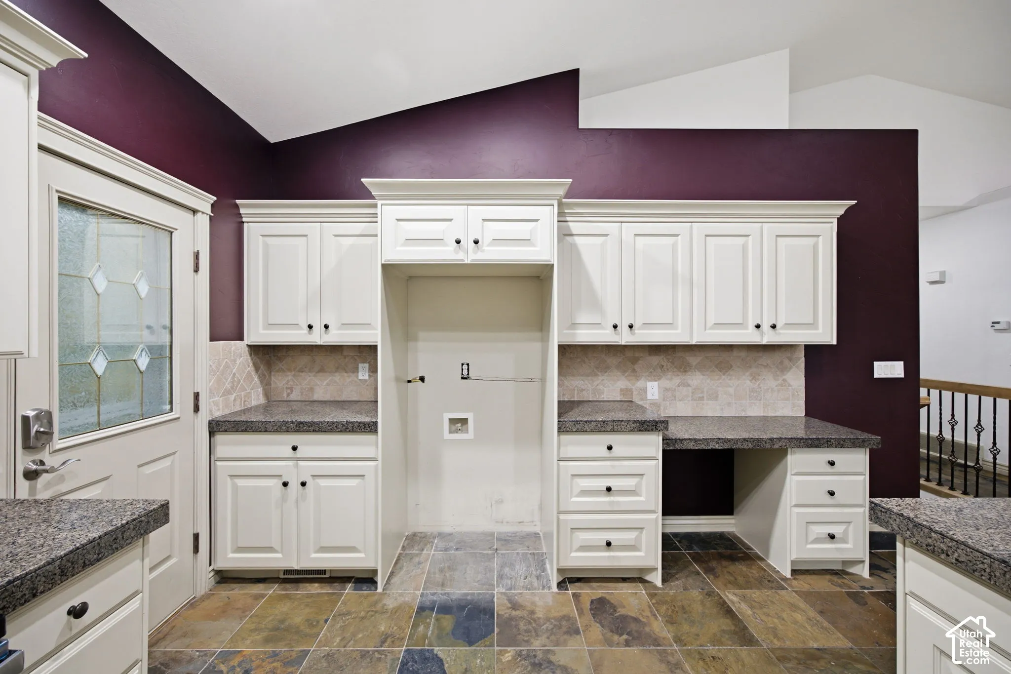 Kitchen featuring white shaker-style cabinetry, stone-finish countertops, diagonal tile backsplash, slate-finish floor tile, and a built-in workspace